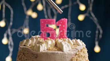 生日蛋糕，51个数字燃烧由较轻的粉红色蜡烛在蓝色的背面。 蜡烛被点燃了。 慢动作